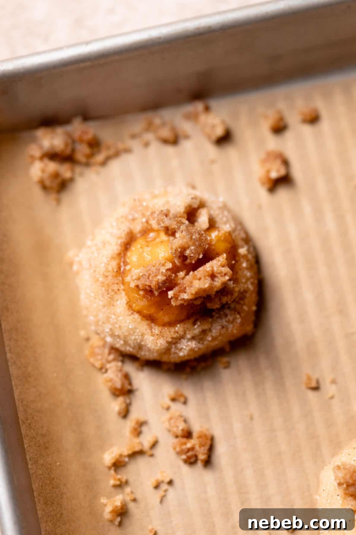 Peach cobbler cookie dough ball on a tray, topped with cinnamon crumb before baking.