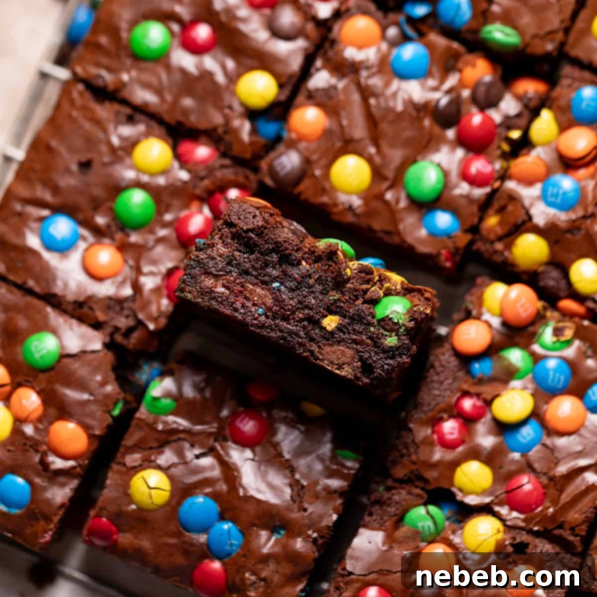 M&M brownies on a wire rack with one on its side to show the delicious fudgy texture.