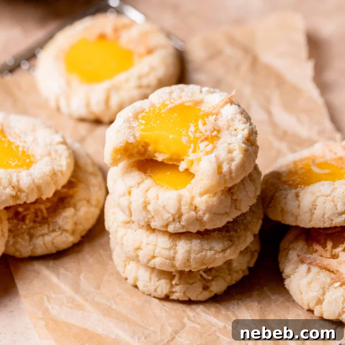A stack of golden-brown mango cookies with a bite taken out of the top one, revealing the rich mango curd.