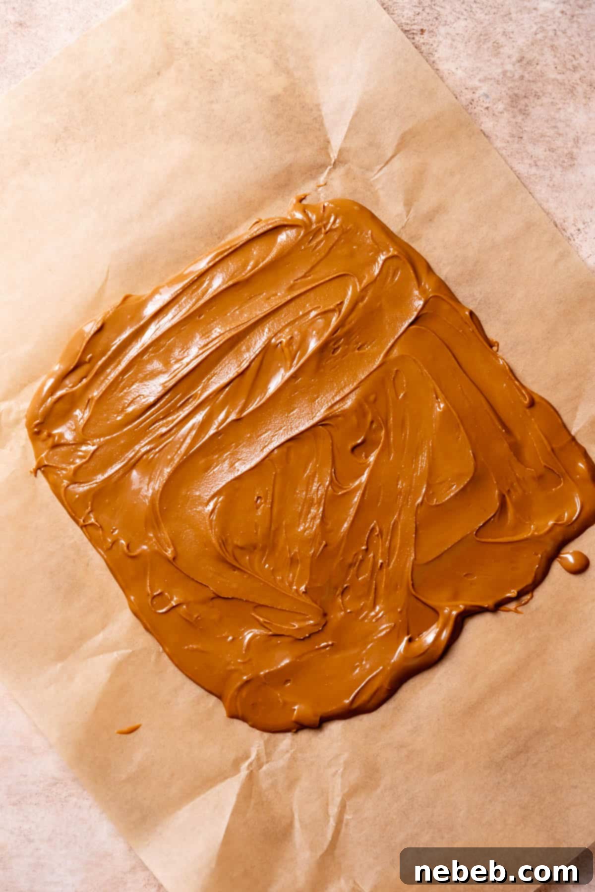 Biscoff cookie butter evenly spread on parchment paper, ready to be frozen.