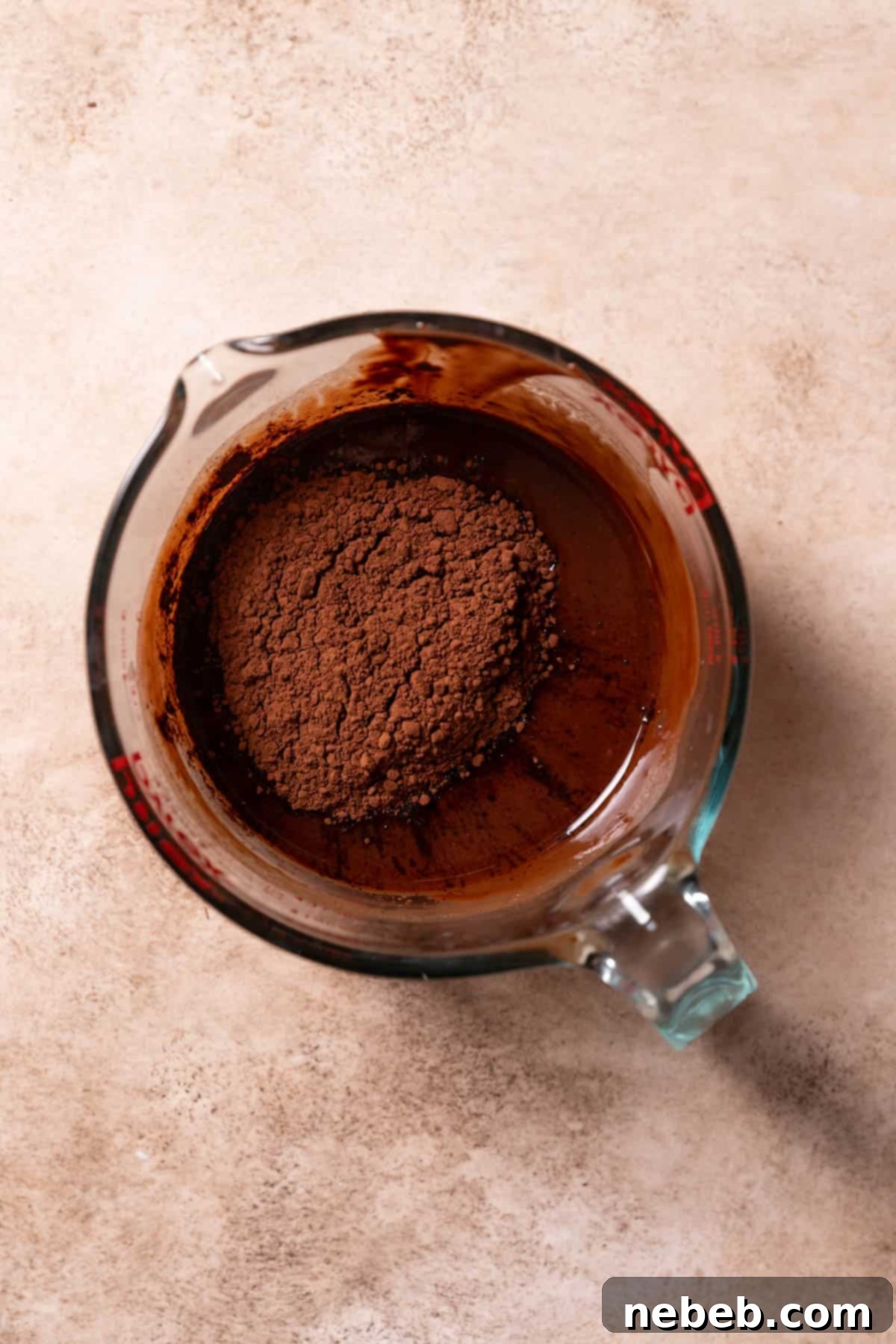 Unsweetened Dutch cocoa powder being whisked into melted butter and chocolate chips.