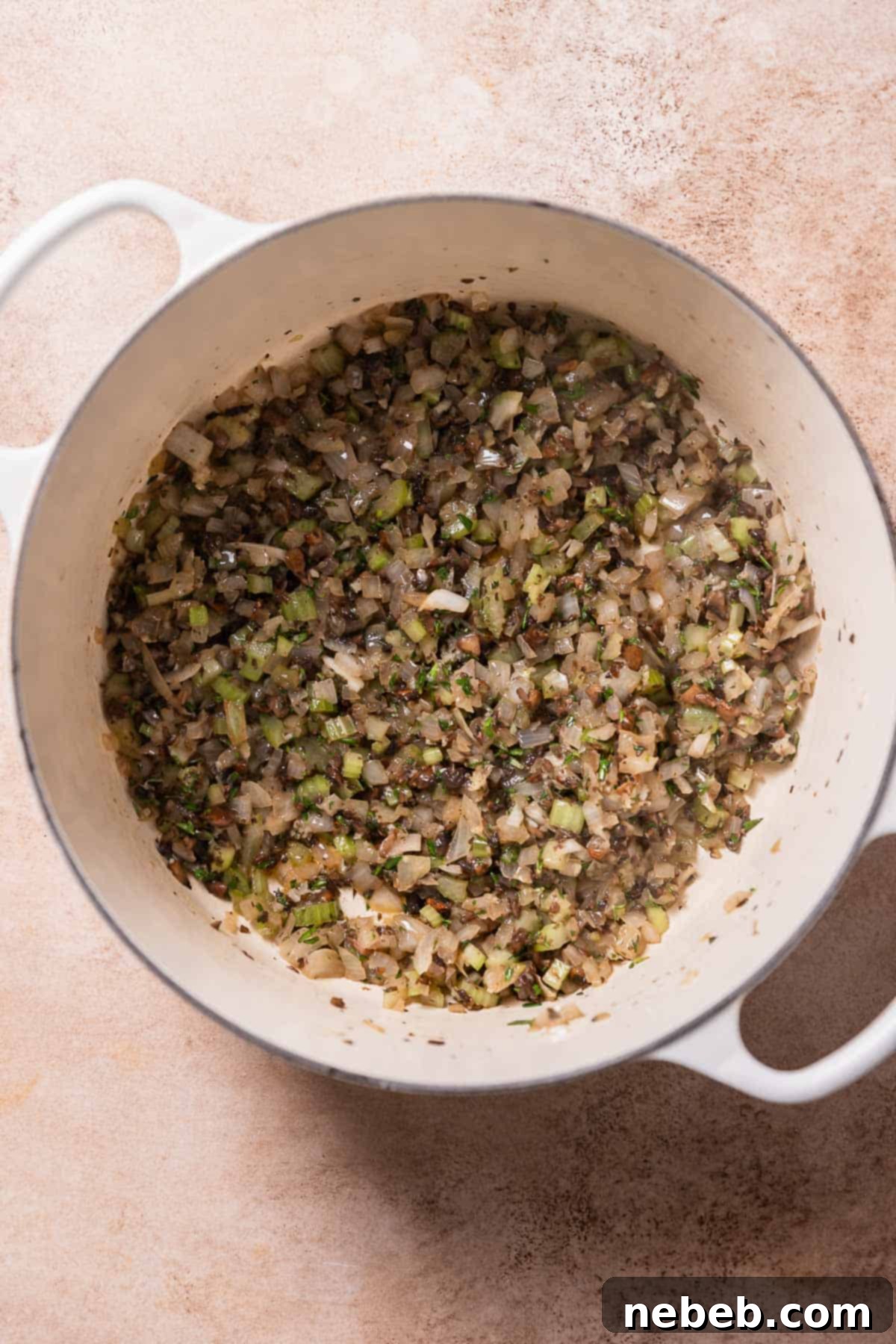 A dutch oven pot with sauteed mushrooms, onion, celery, and fresh herbs.