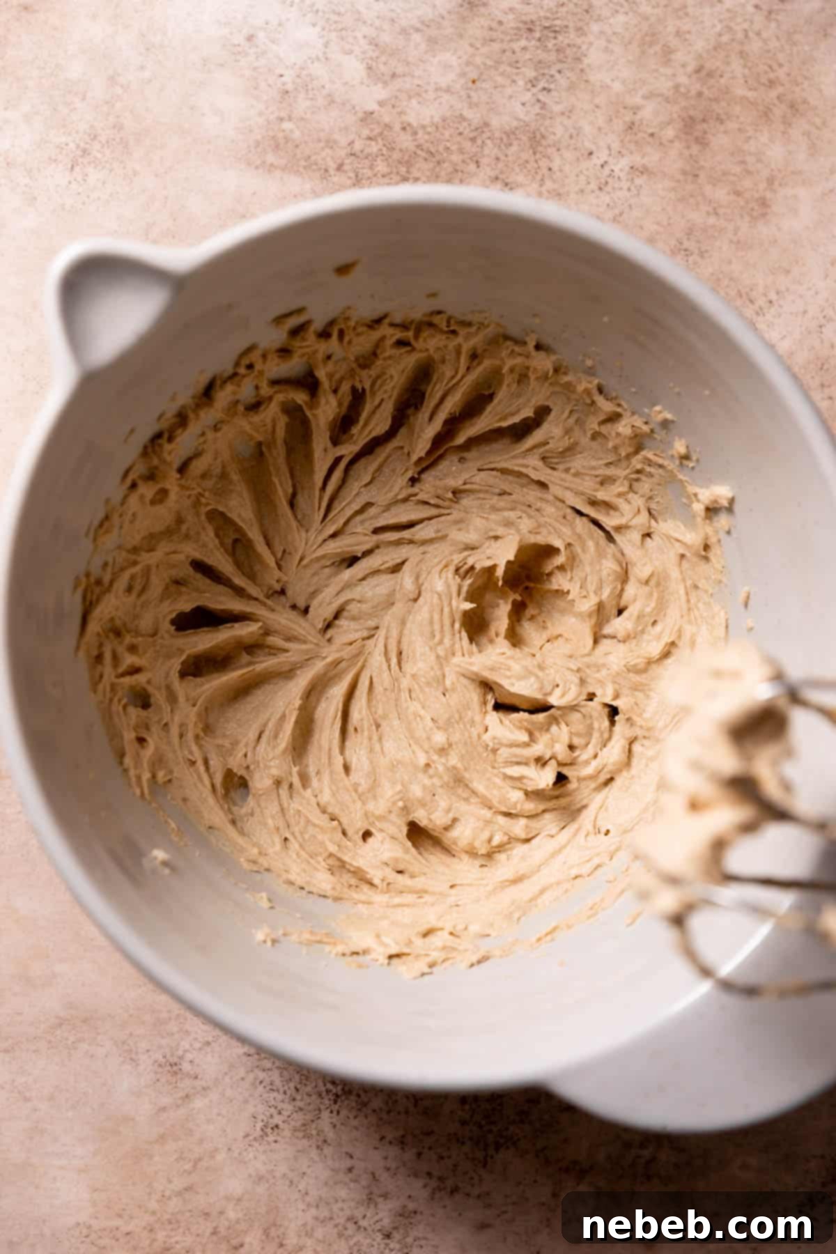 Butter, sugar, and eggs smoothly mixed together in a large bowl.