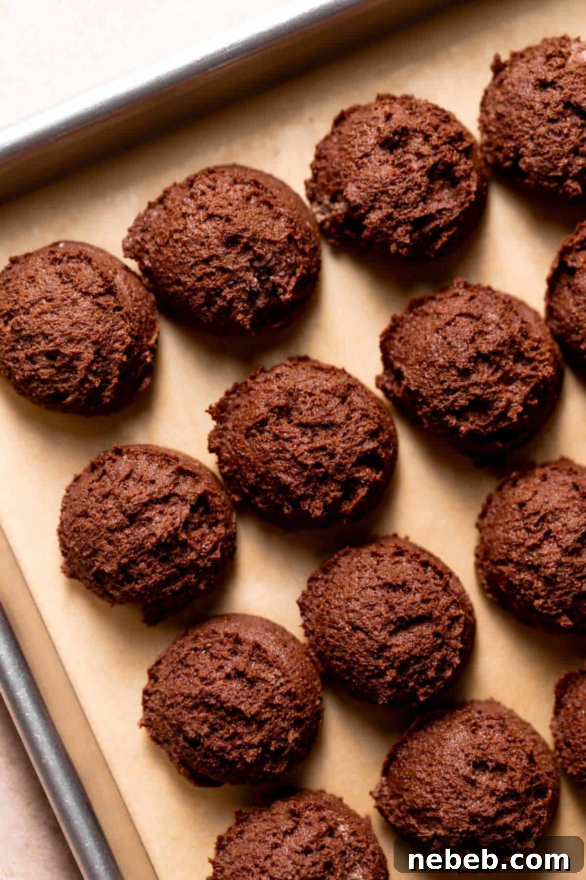 Scooped chocolate cookie dough balls neatly arranged on a baking tray, ready for chilling.
