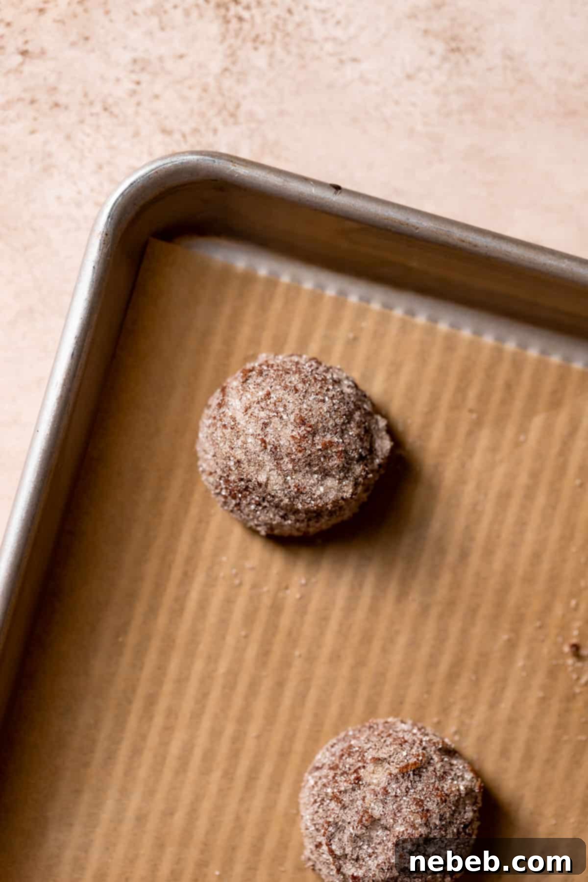 Perfectly baked chocolate snickerdoodle cookie dough balls with crackled tops on a baking tray, cooling down.