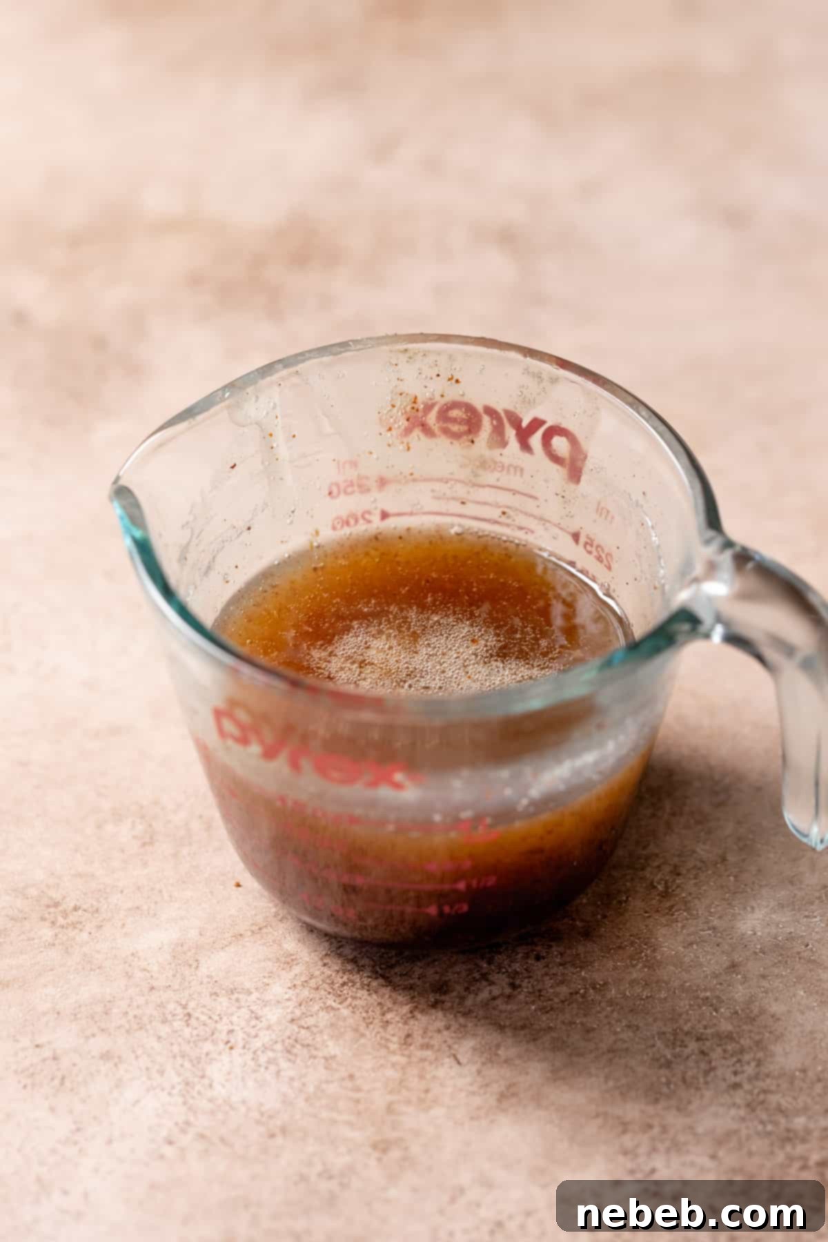 A glass measuring cup containing chilled, thickened brown butter, ready for mixing.