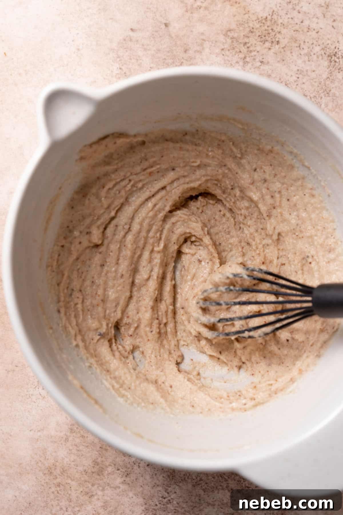A mixing bowl showcasing the light, sandy mixture of creamed brown butter and sugars after vigorous whisking.
