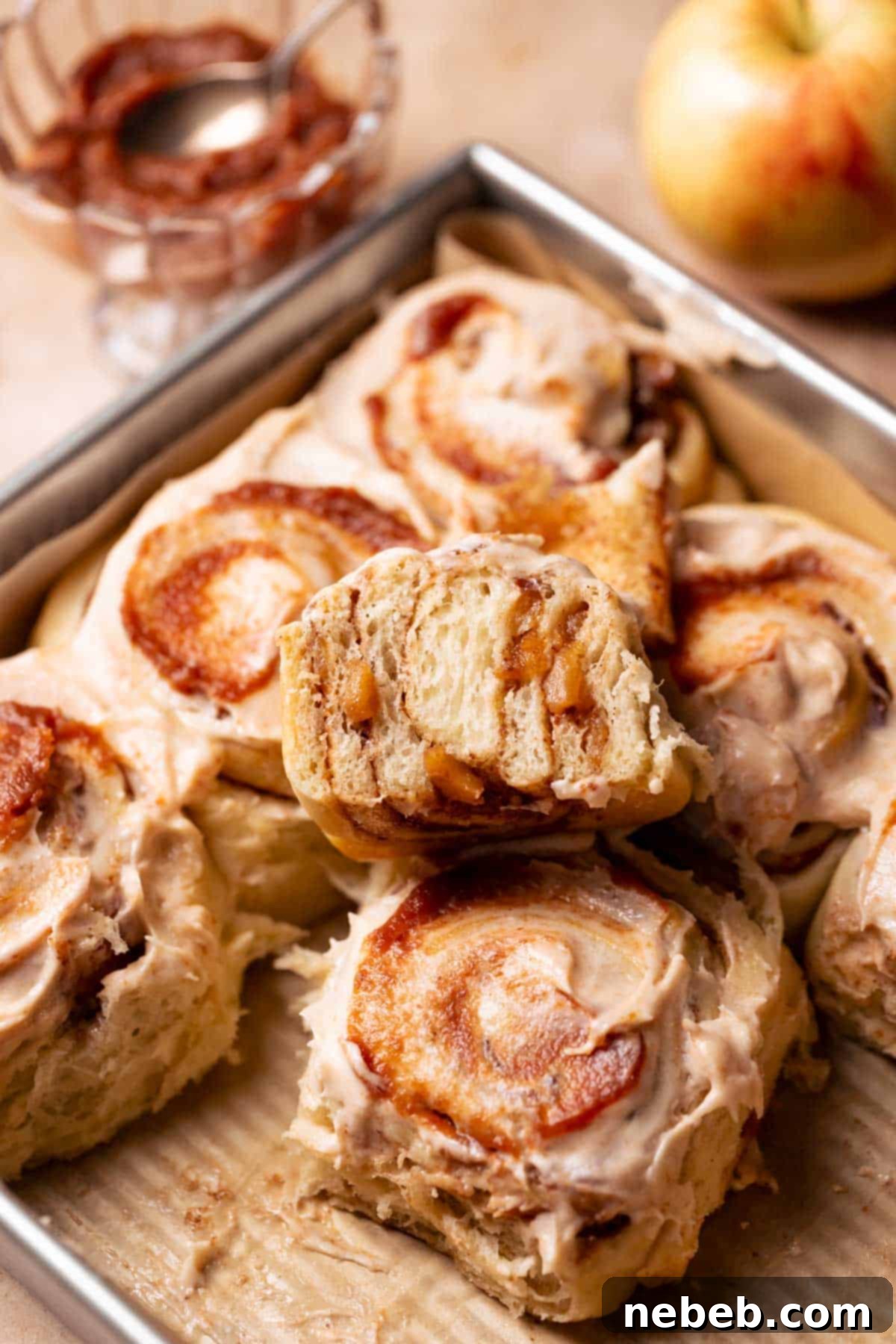 A cinnamon roll cut in half to show the apple pie filling.