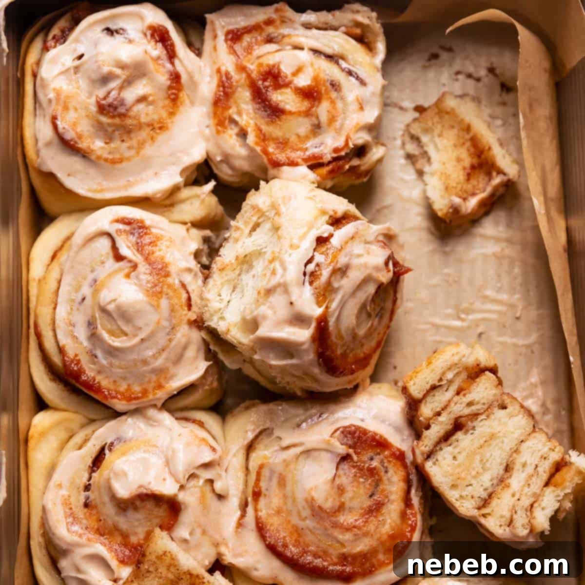 Apple cinnamon rolls in a baking pan with cream cheese icing and apple butter swirled on top.