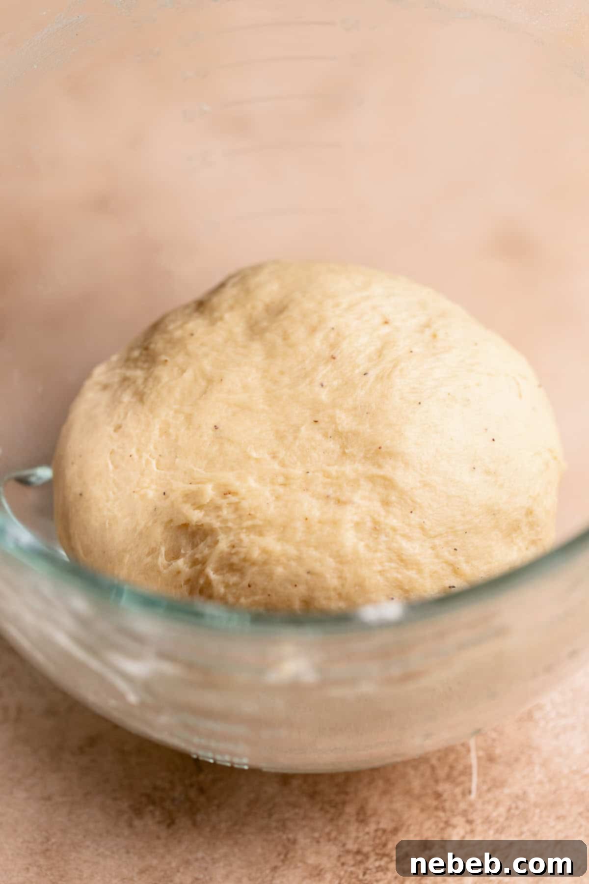 Cinnamon roll dough ball in a glass mixer bowl.