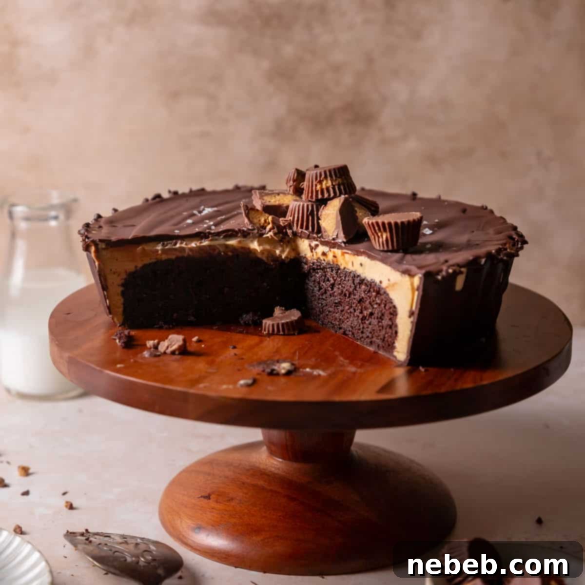 Reese's peanut butter cake on a wooden cake stand with slices missing to show the filling.
