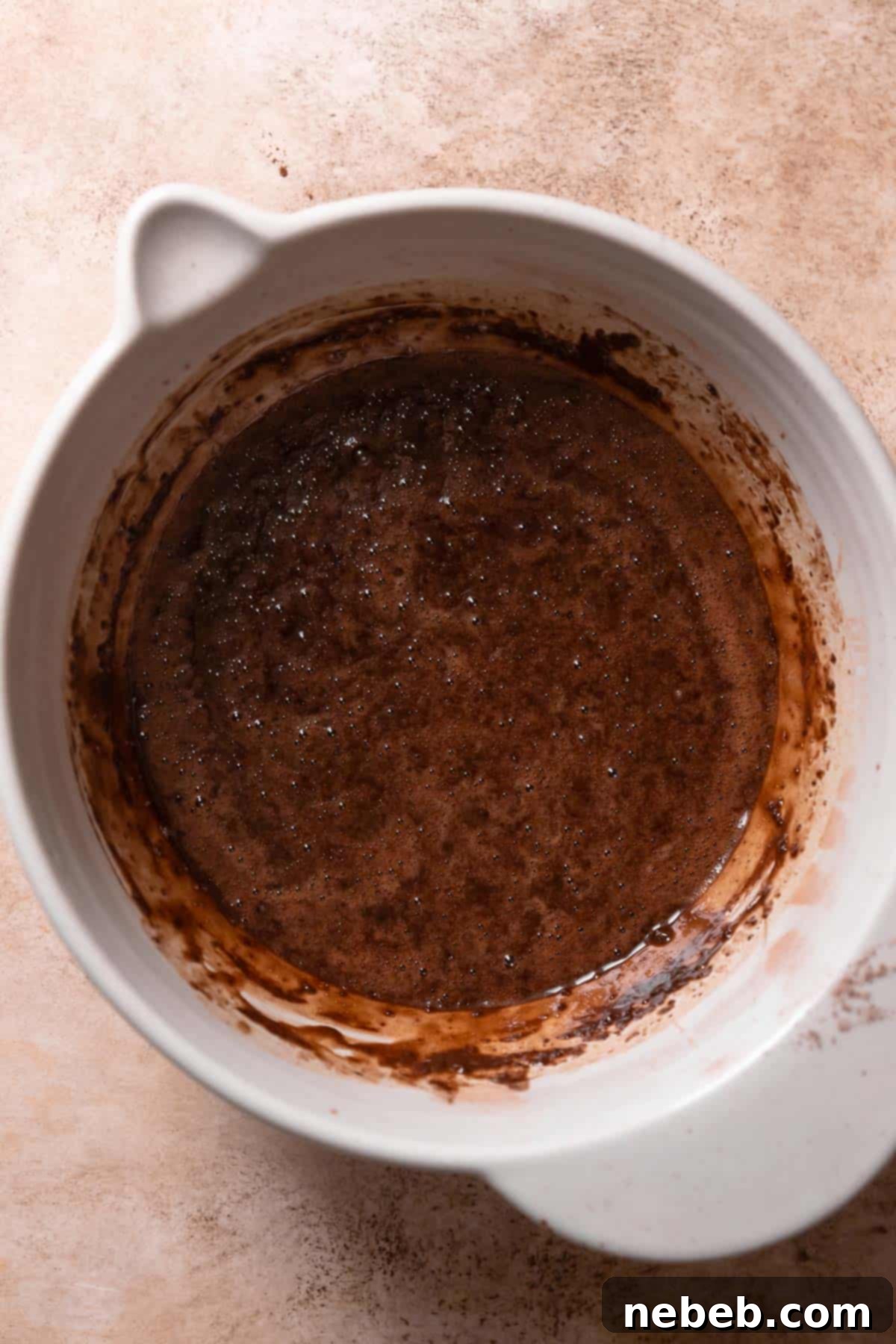A mixing bowl filled with rich, dark chocolate cake batter, ready for baking.