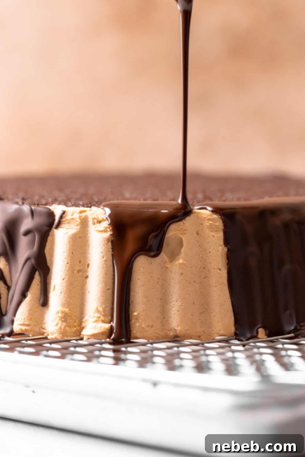 A luxurious stream of glossy chocolate ganache being poured over the edge of the Reese's cake, creating perfect drips down the sides.