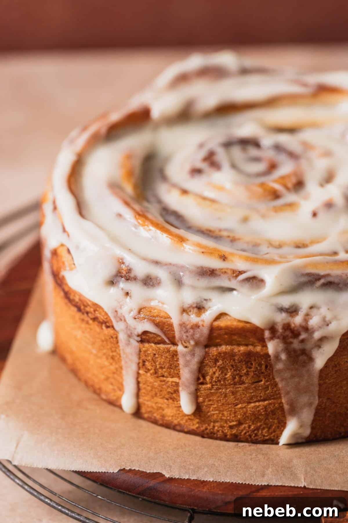 Cinnamon bun cake topped with cream cheese icing on a wooden serving platter.