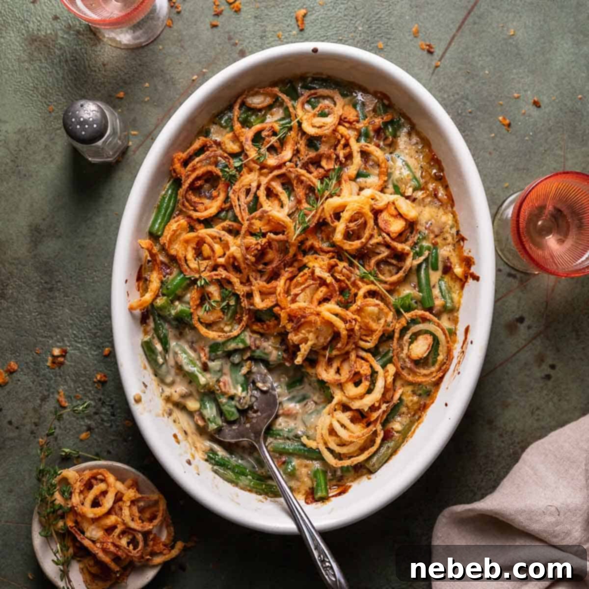 Cheesy green bean casserole in a white baking dish with fried onions on top.