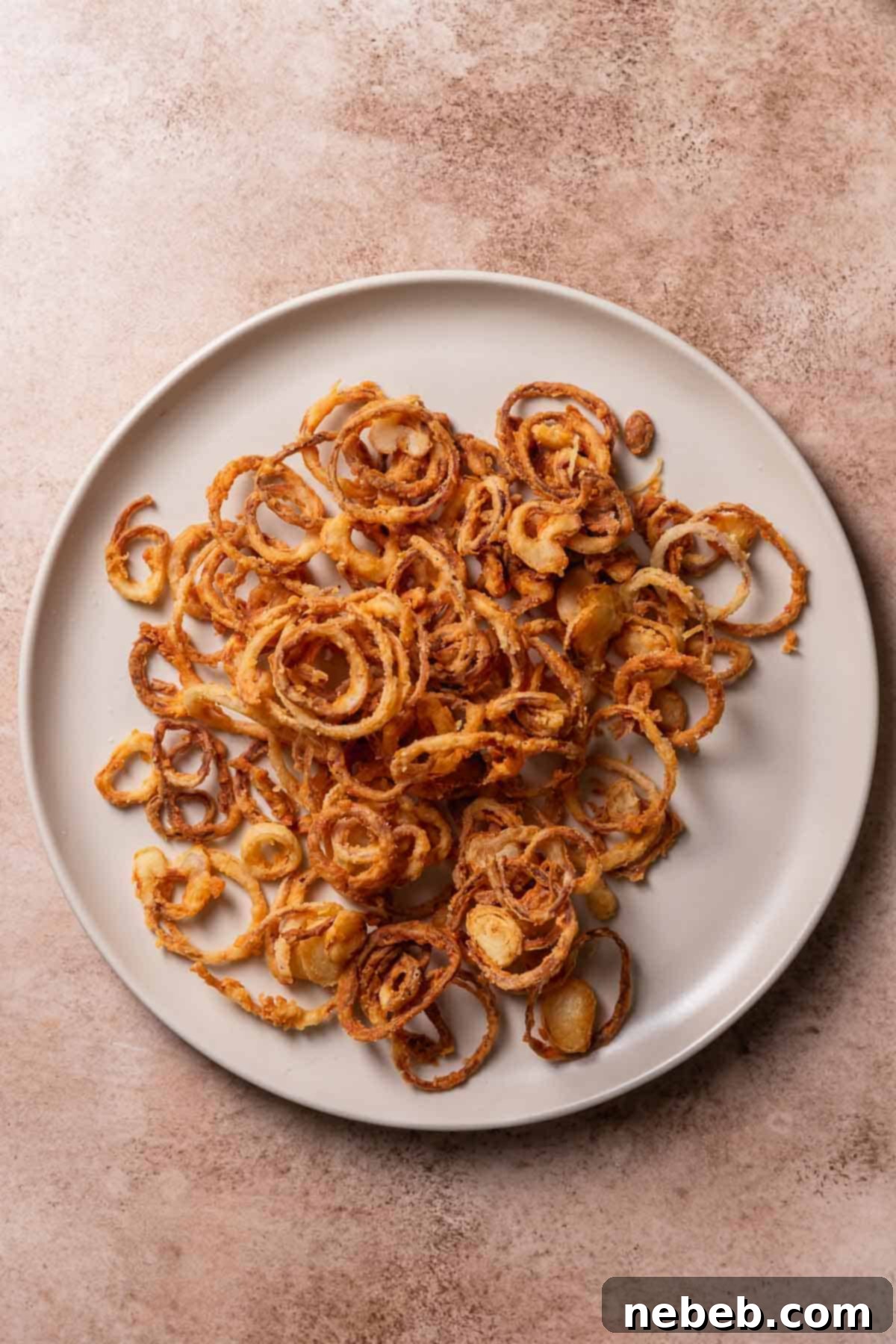 Golden brown crispy fried shallots on a beige plate, seasoned with salt.