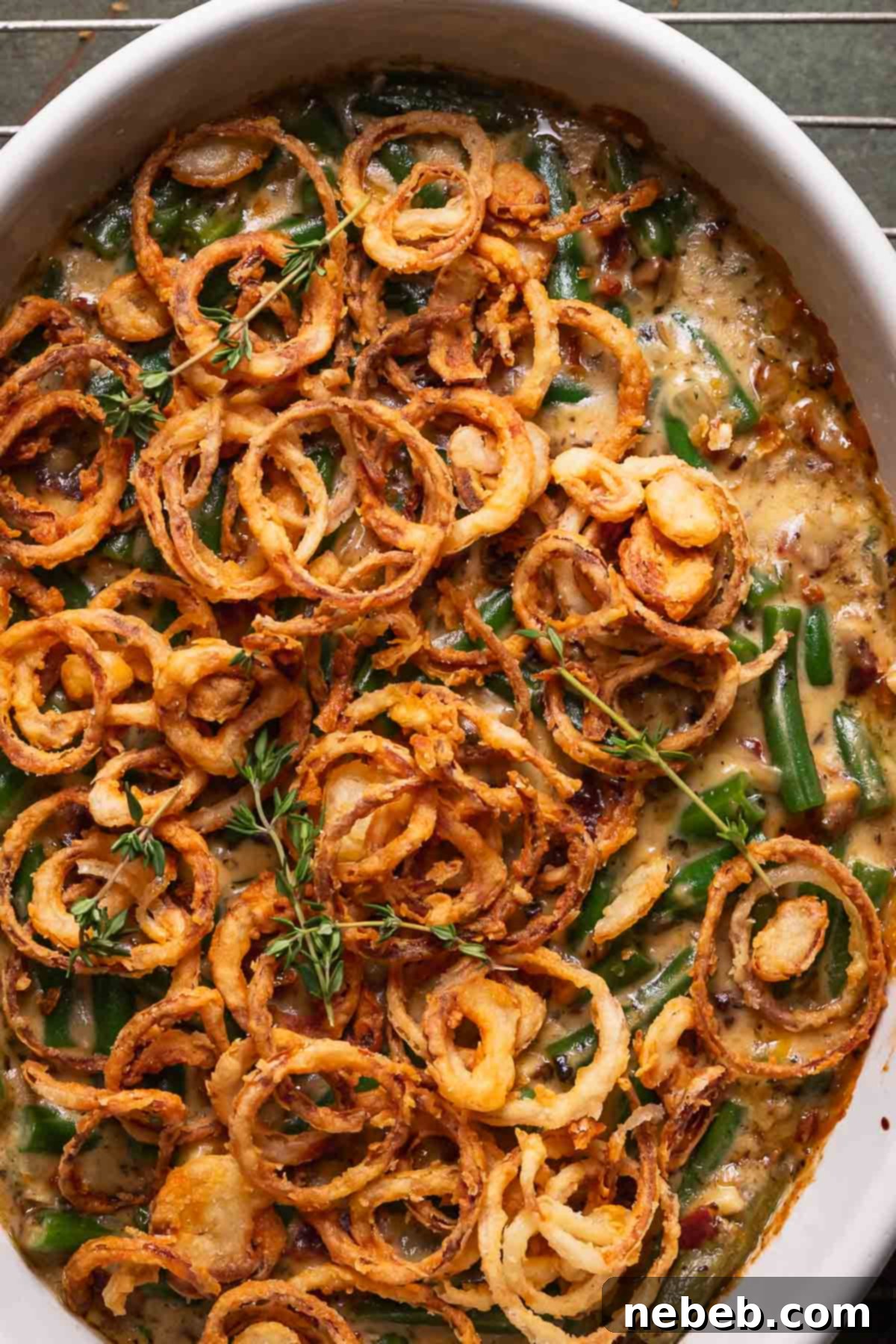 Baked green bean and cheese casserole in a baking dish, topped with homemade fried shallots.