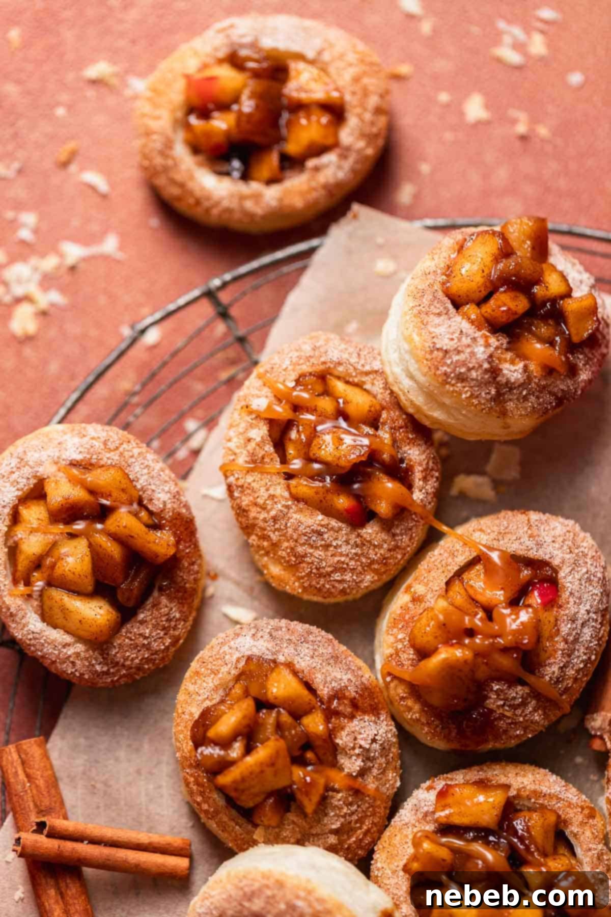 Mini apple pie cookies drizzled with caramel sauce on a wire rack.