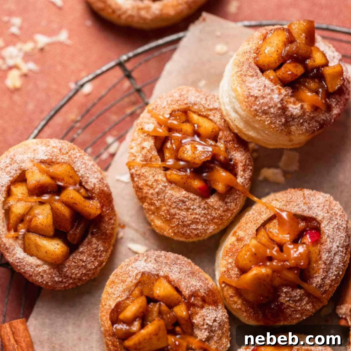 Apple pie filled cookies with caramel sauce drizzled on top on parchment paper.