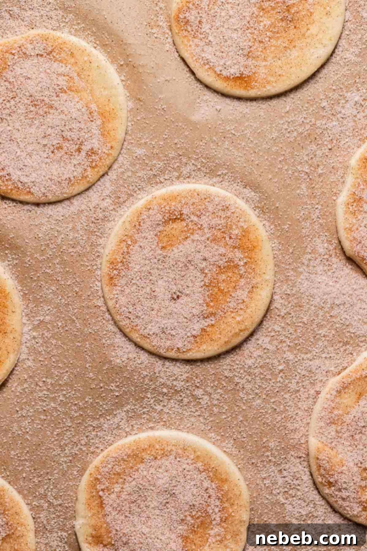 Puff pastry rounds on a baking sheet brushed with egg wash and sprinkled heavily with cinnamon sugar.