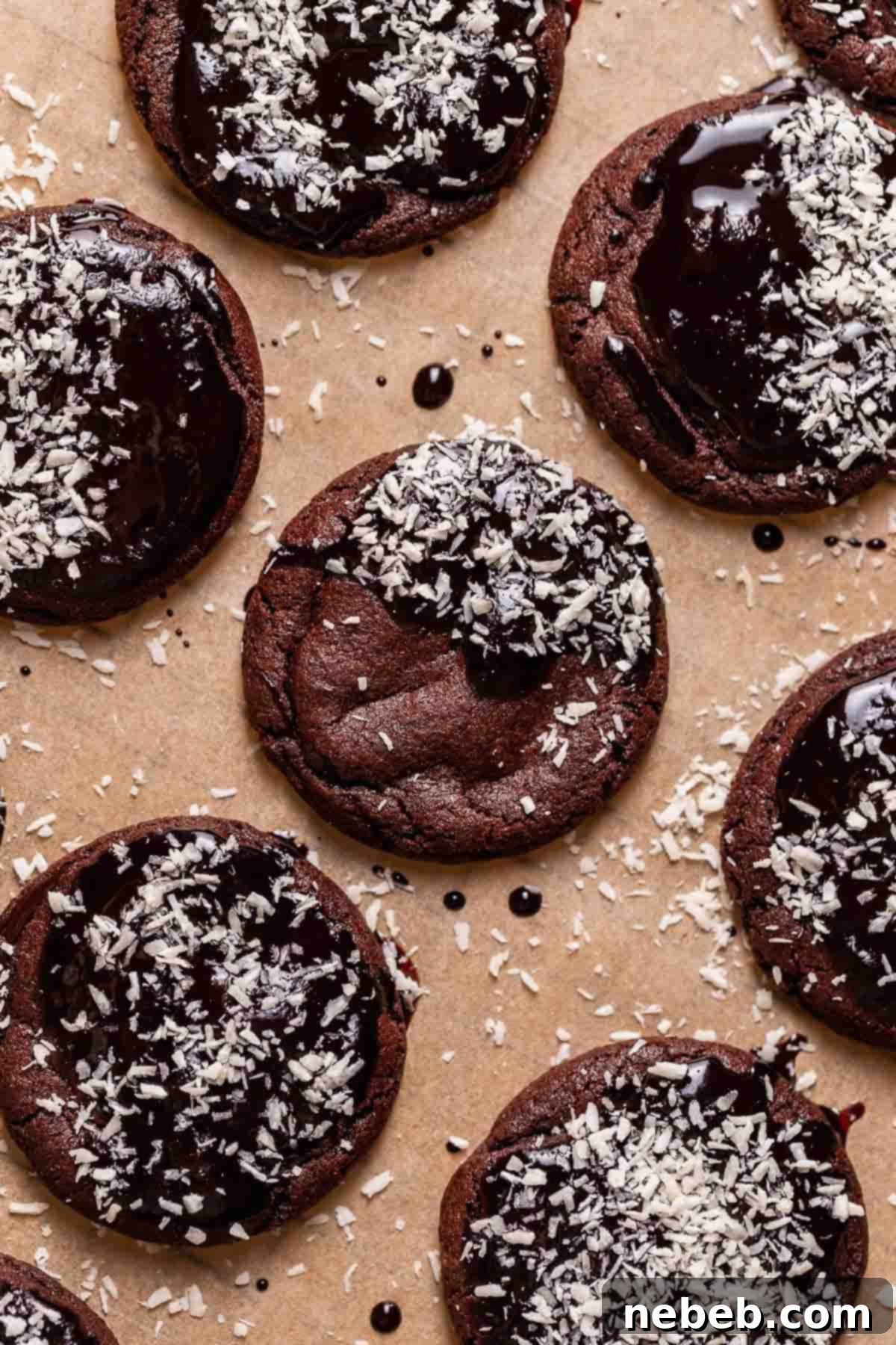 Chocolate lamington cookies on brown parchment paper sprinkled with desiccated coconut.