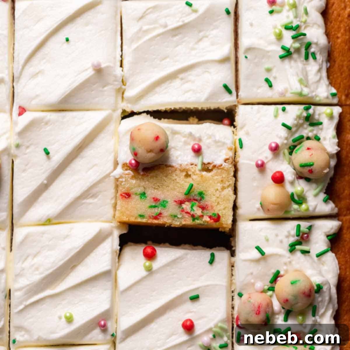 A slice of sugar cookie cake on its side to show the sugar cookie dough layer, frosted and ready to eat.