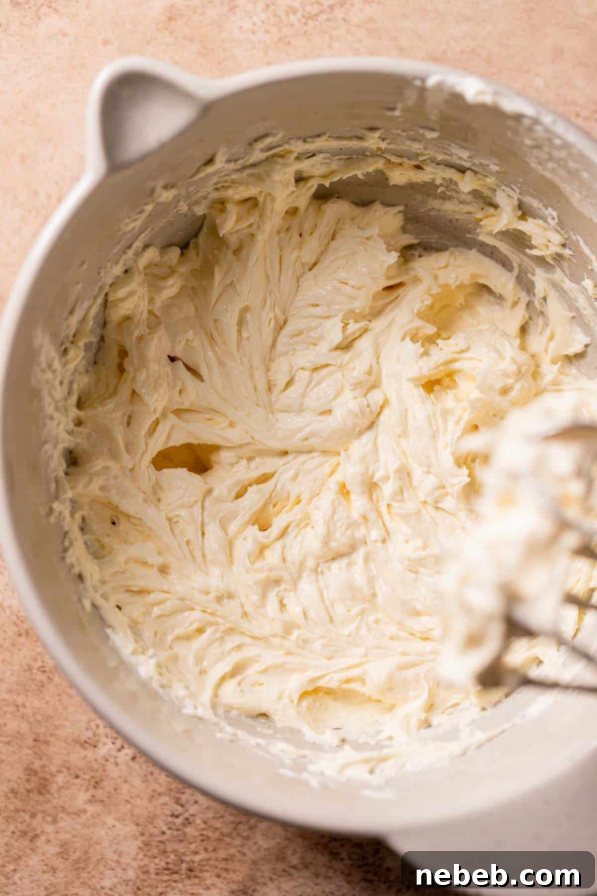 Vanilla cake batter in a mixing bowl after the addition of sour cream and eggs, showing a smooth and well-combined consistency.