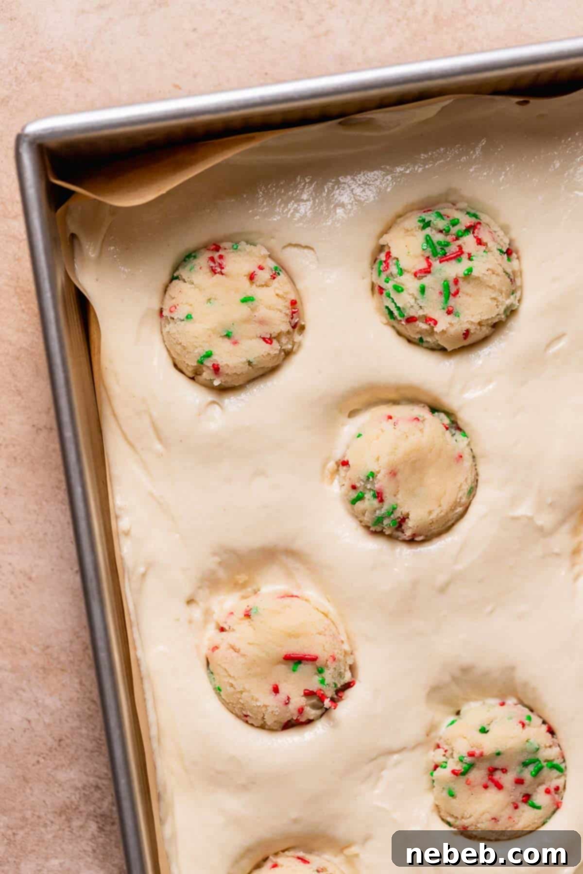 A 9x13 baking pan filled with vanilla cake batter, with chilled sugar cookie dough balls carefully pressed into the surface, ready for baking.