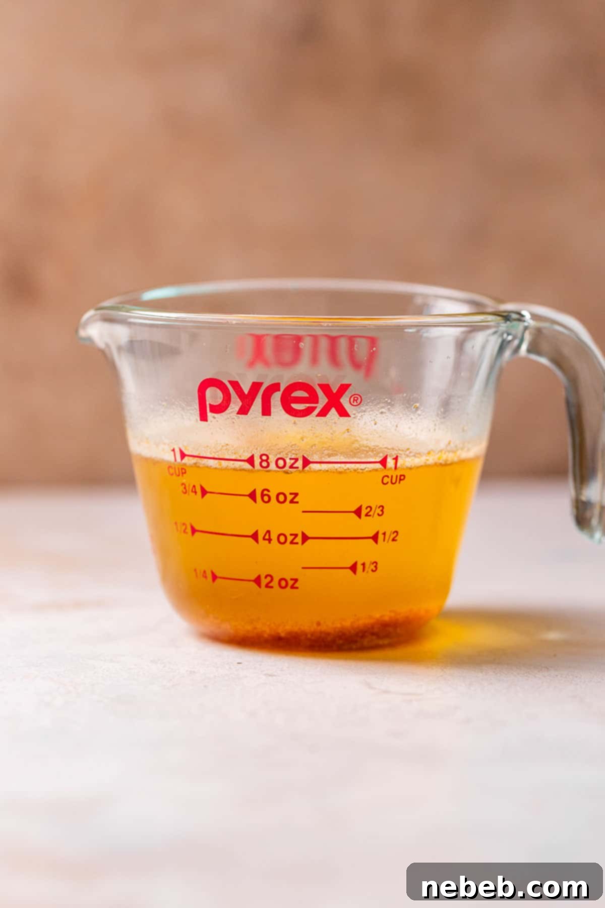 A glass Pyrex measuring cup with browned American butter, demonstrating the difference in moisture loss compared to European butter.