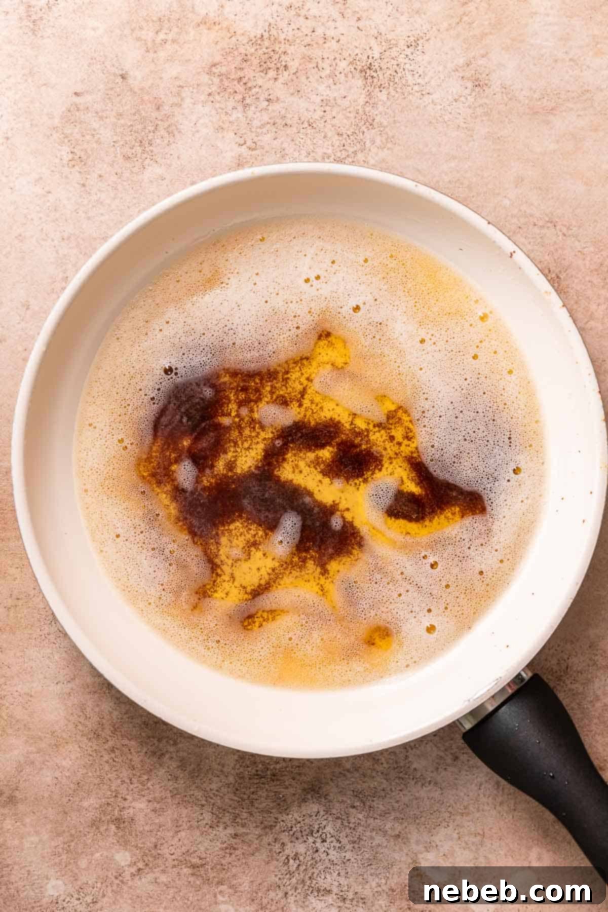 A white pan with burnt brown butter, showing black milk solids and a darkened liquid.