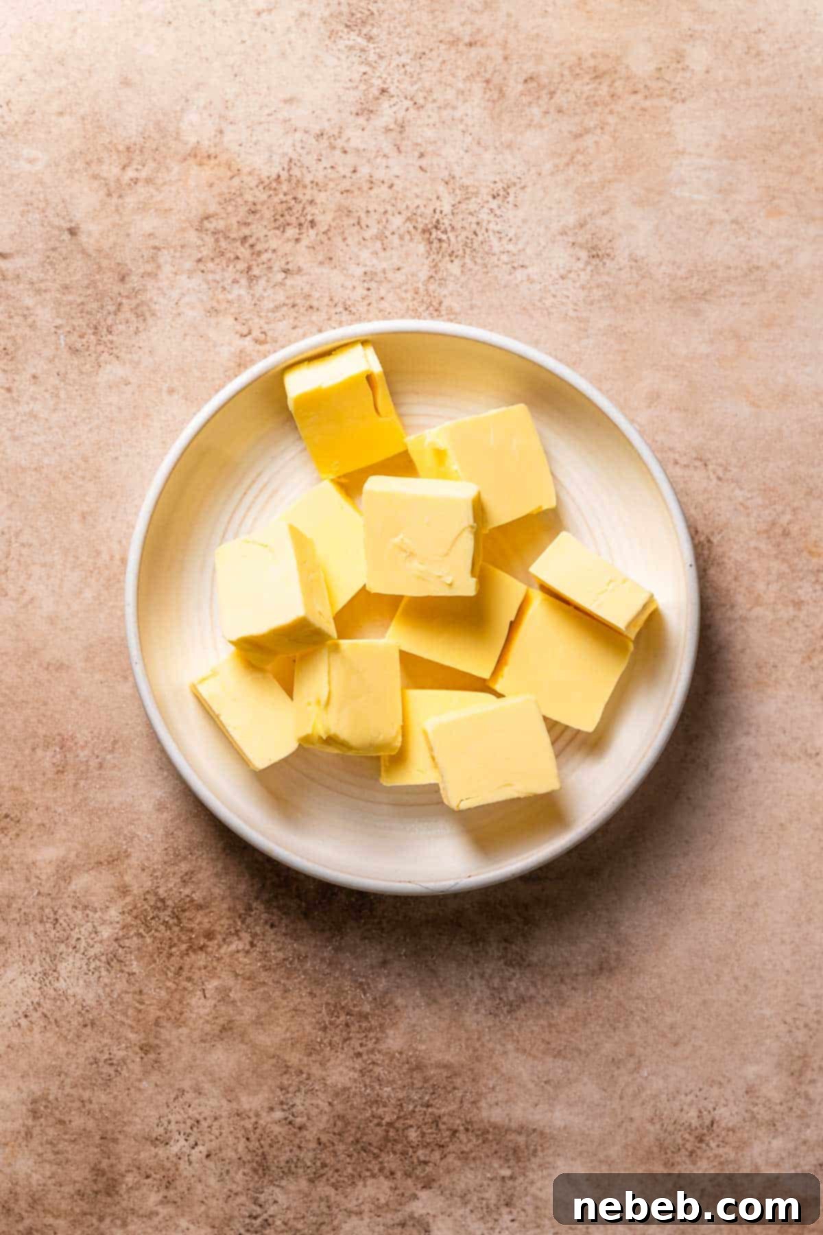 A white bowl with neatly sliced butter sticks, ready for browning.