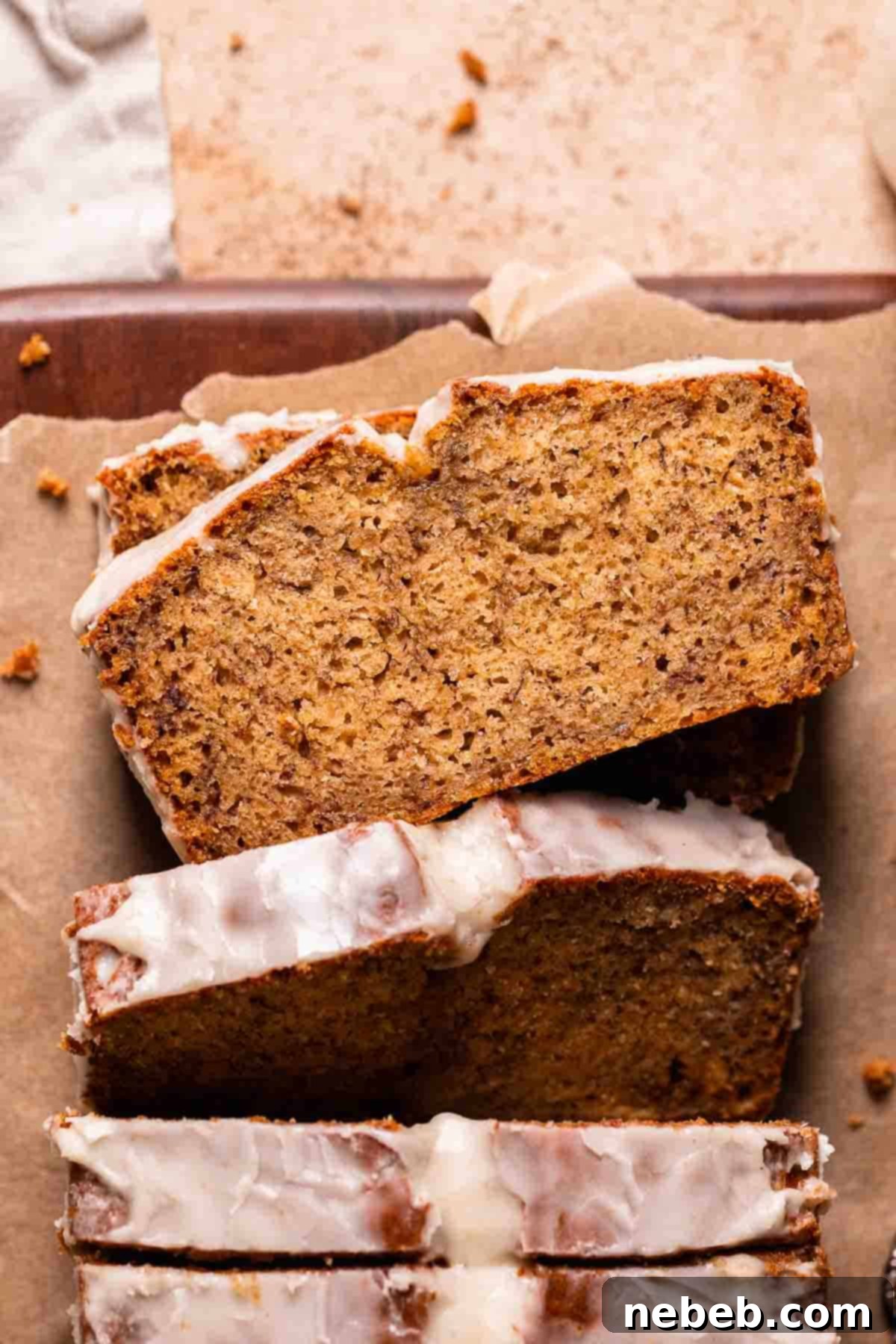 A loaf of brown butter banana bread on brown parchment paper with a slice laying flat to show the moist texture.