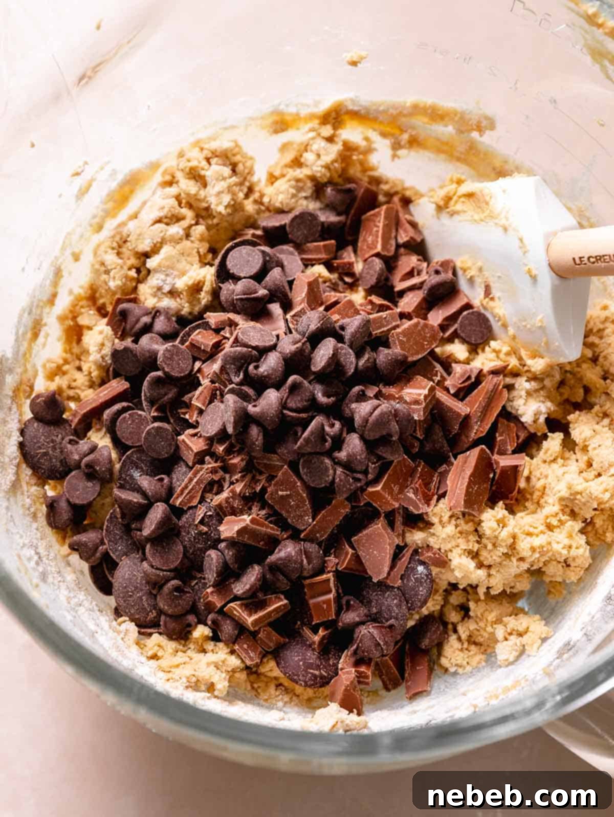 A pile of chocolate chips on top of the cookie dough before mixing.