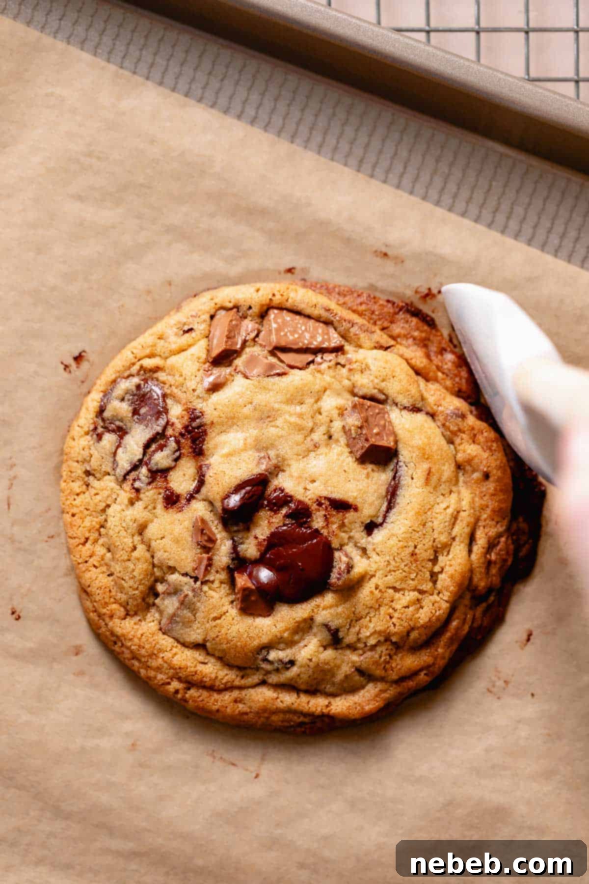 A spatula scooting in the edges of a cookie after baking to make it perfectly round.