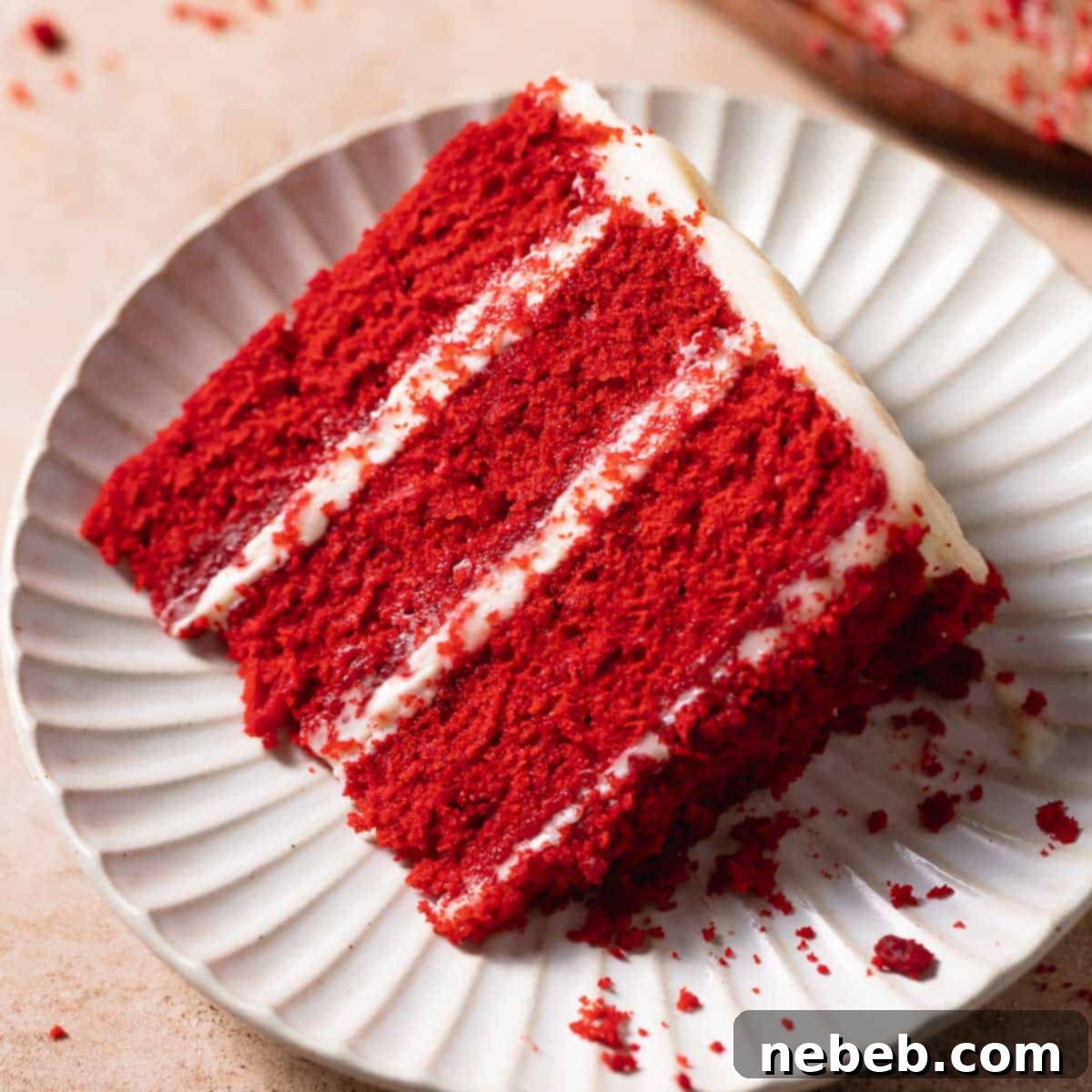 A delicious slice of moist red velvet cake with cream cheese frosting on a white plate, ready to be enjoyed.