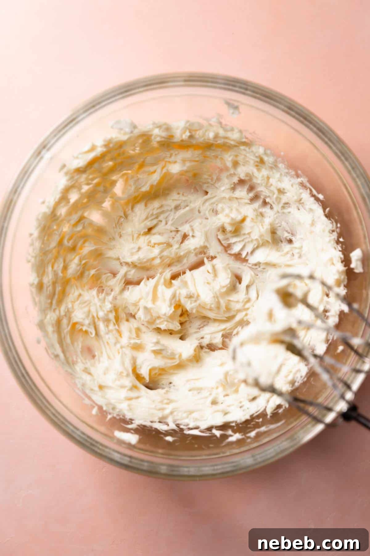 A glass mixing bowl with the creamed butters and cream cheese.