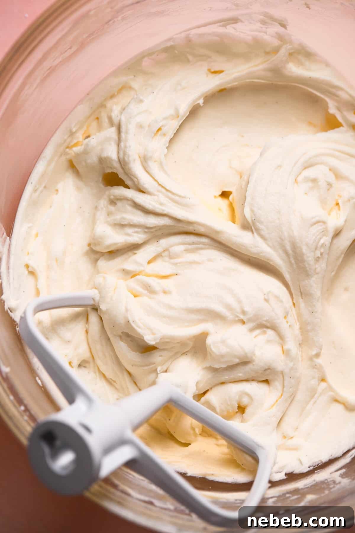 A glass mixing bowl with cream cheese frosting.