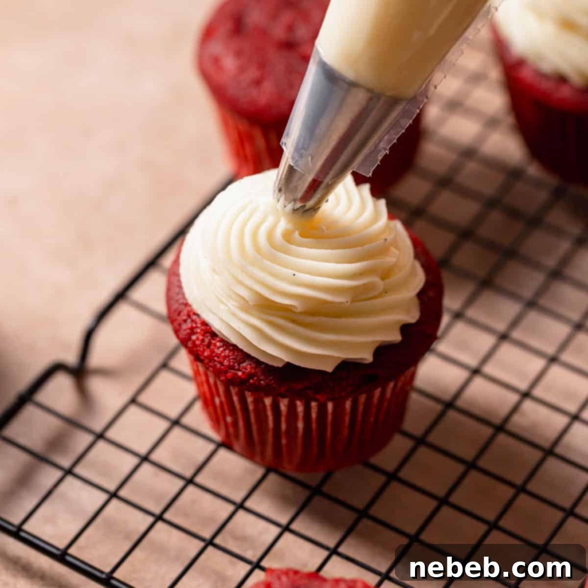 Cream cheese frosting being piped on top of a cupcake.