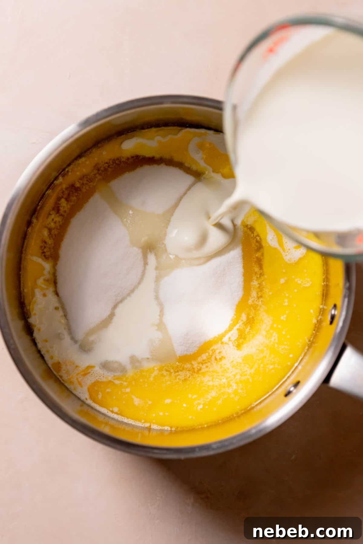 Pouring heavy cream into a pot with melted butter and sugar.