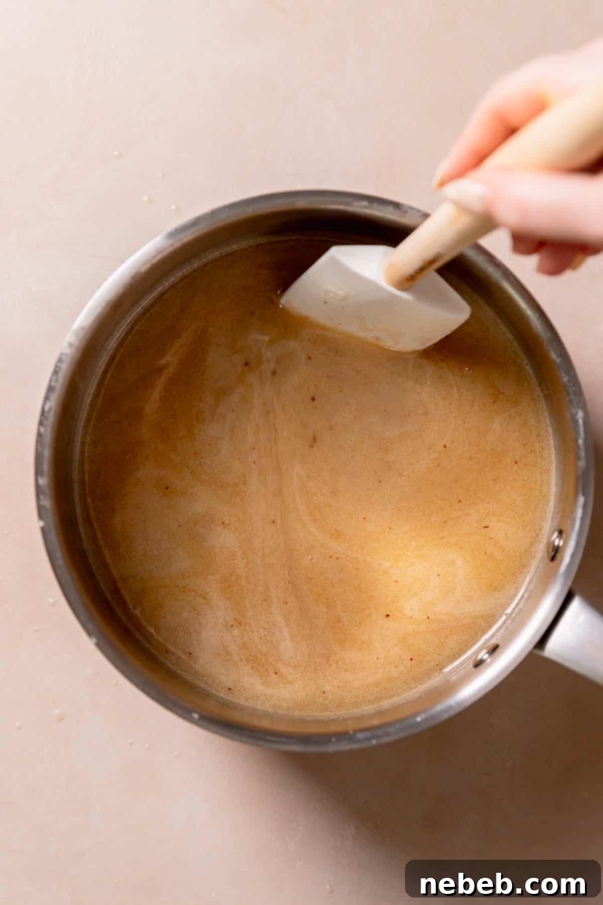 A pot with chocolate chips being melted into butter and sugar.