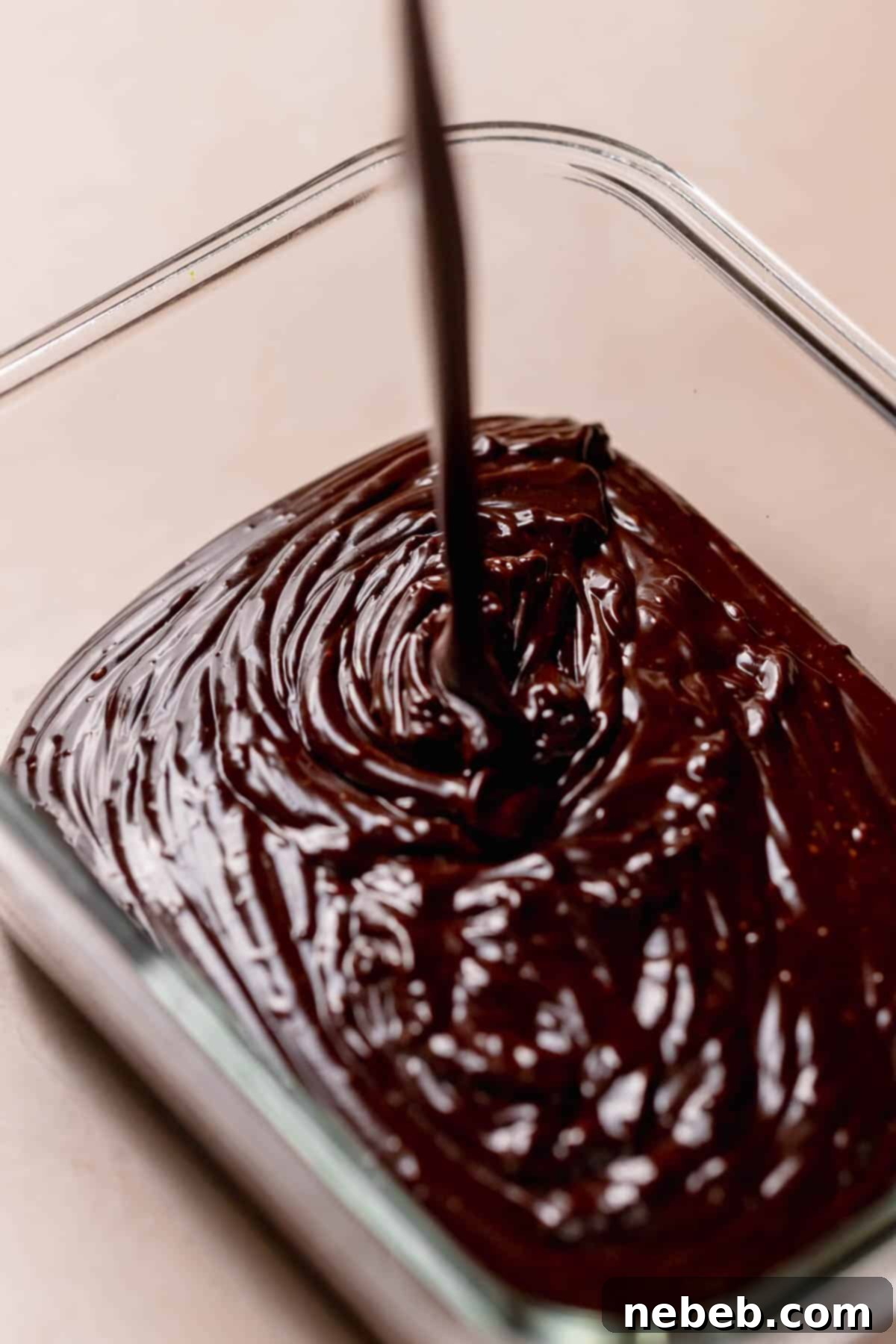 The chocolate fudge icing being poured into a container to set overnight.
