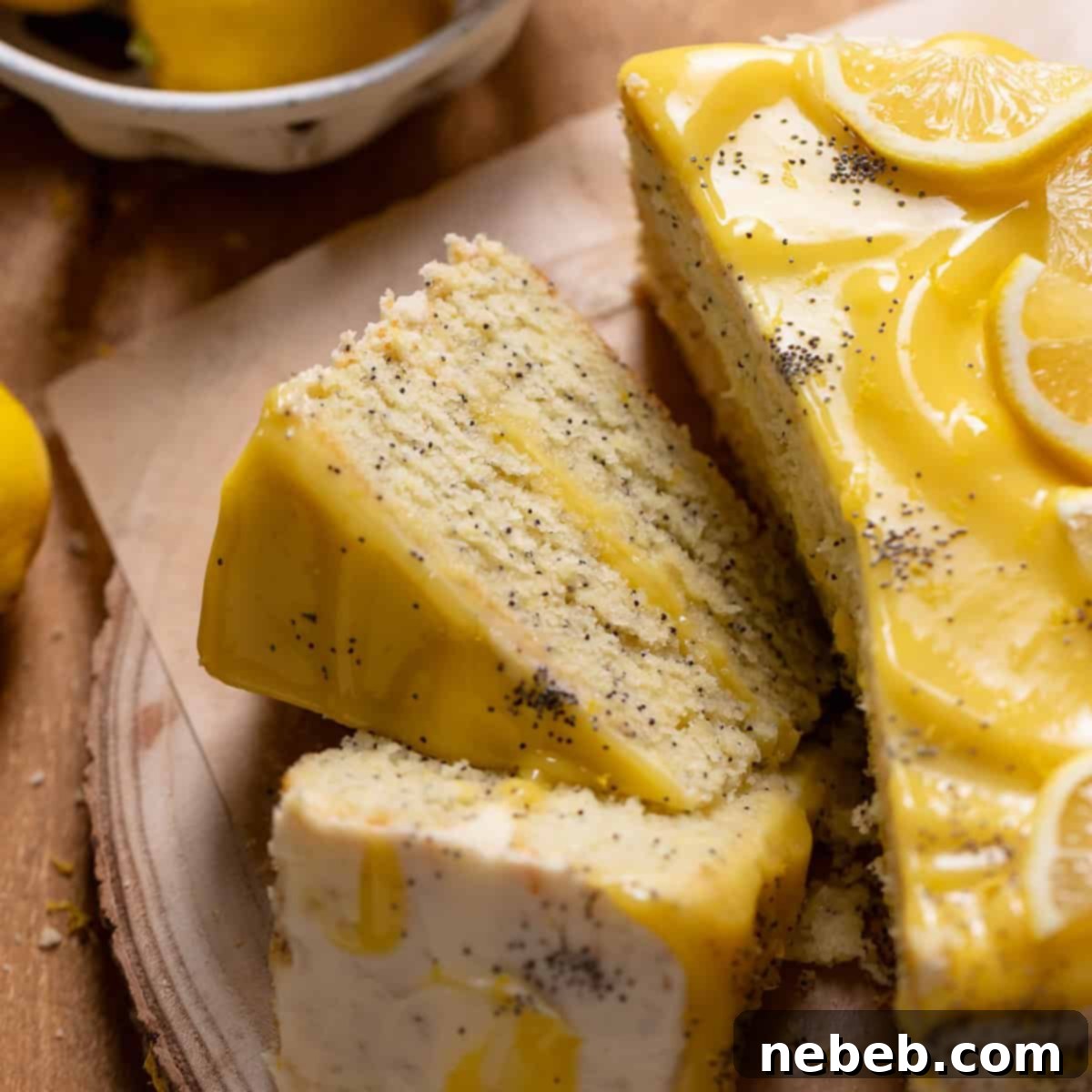 Lemon poppy seed layer cake cut into slices on a wooden platter.