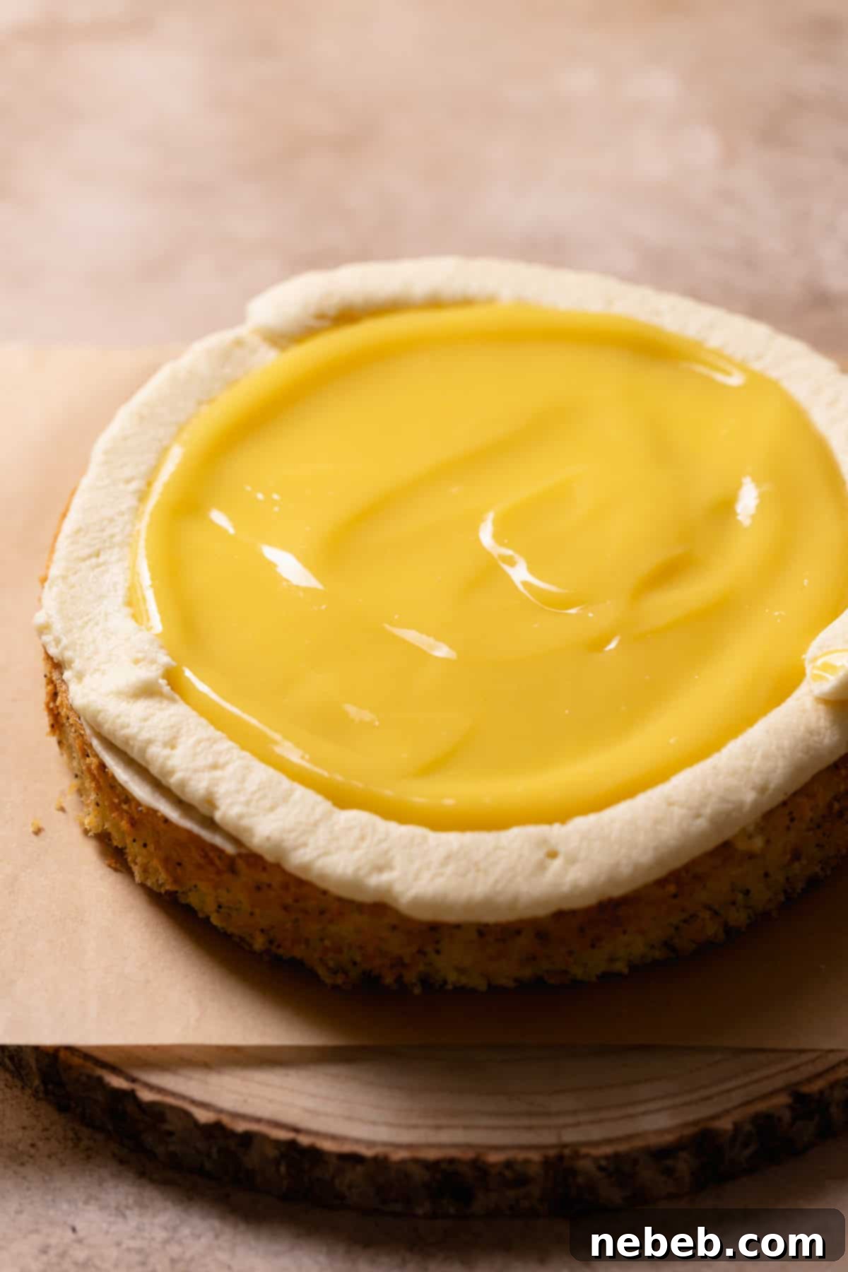 A layer of lemon cake on a platter with cream cheese frosting border and lemon curd center.