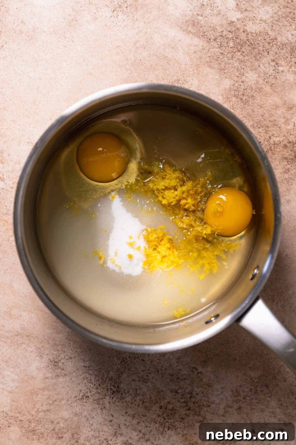 Ingredients for homemade lemon curd, including sugar, lemon zest, eggs, lemon juice, and a pinch of salt, combined in a pot before whisking.