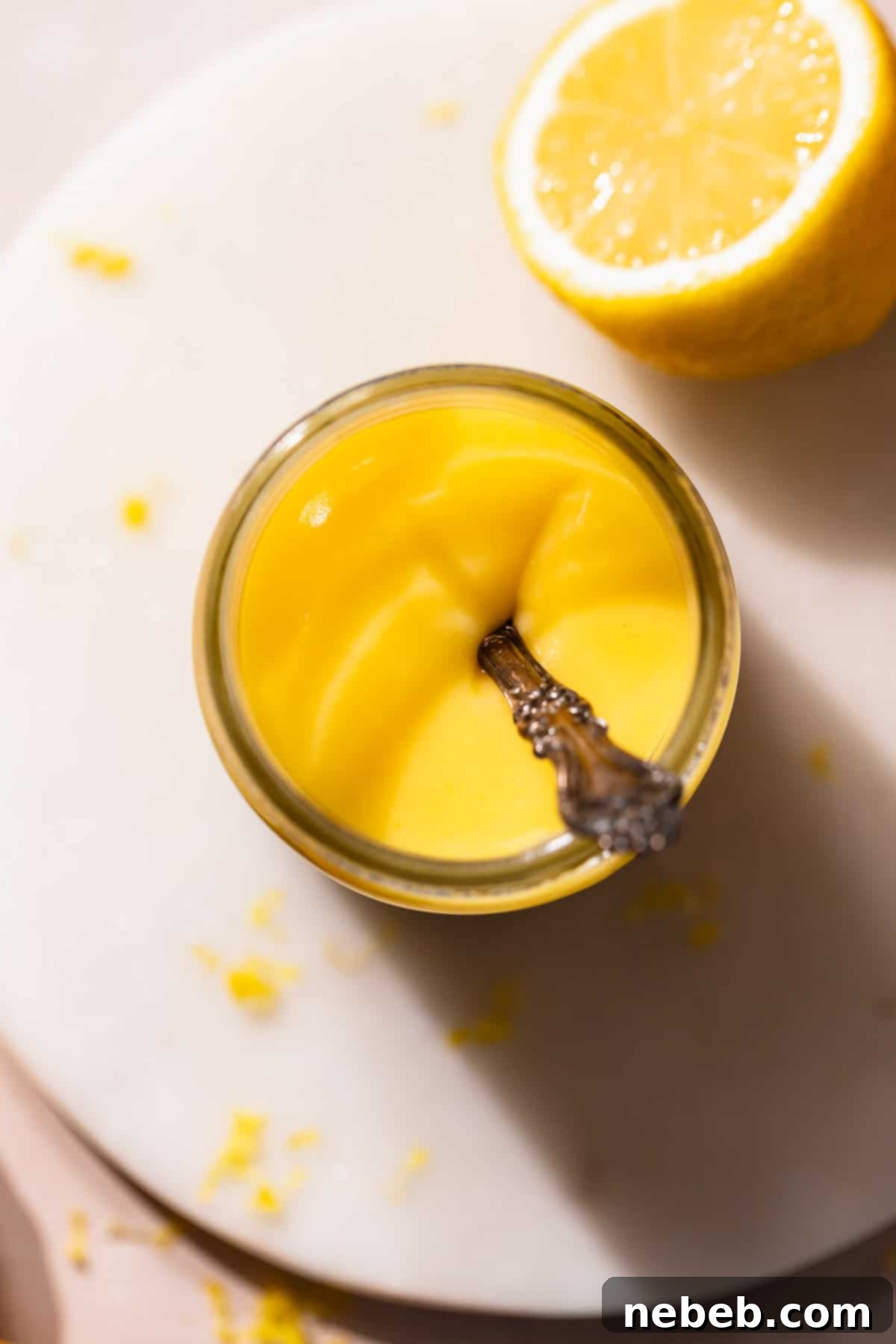 A clear glass mason jar filled to the brim with beautifully golden homemade lemon curd, ready for chilling and enjoyment.