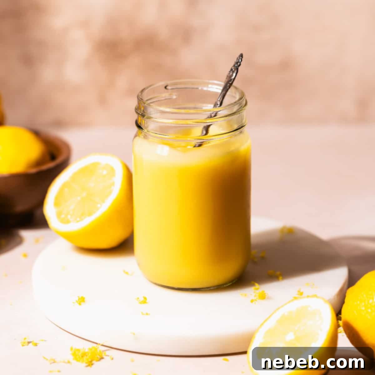 Homemade lemon curd in a glass mason jar with a spoon dipping into it, ready to be enjoyed.