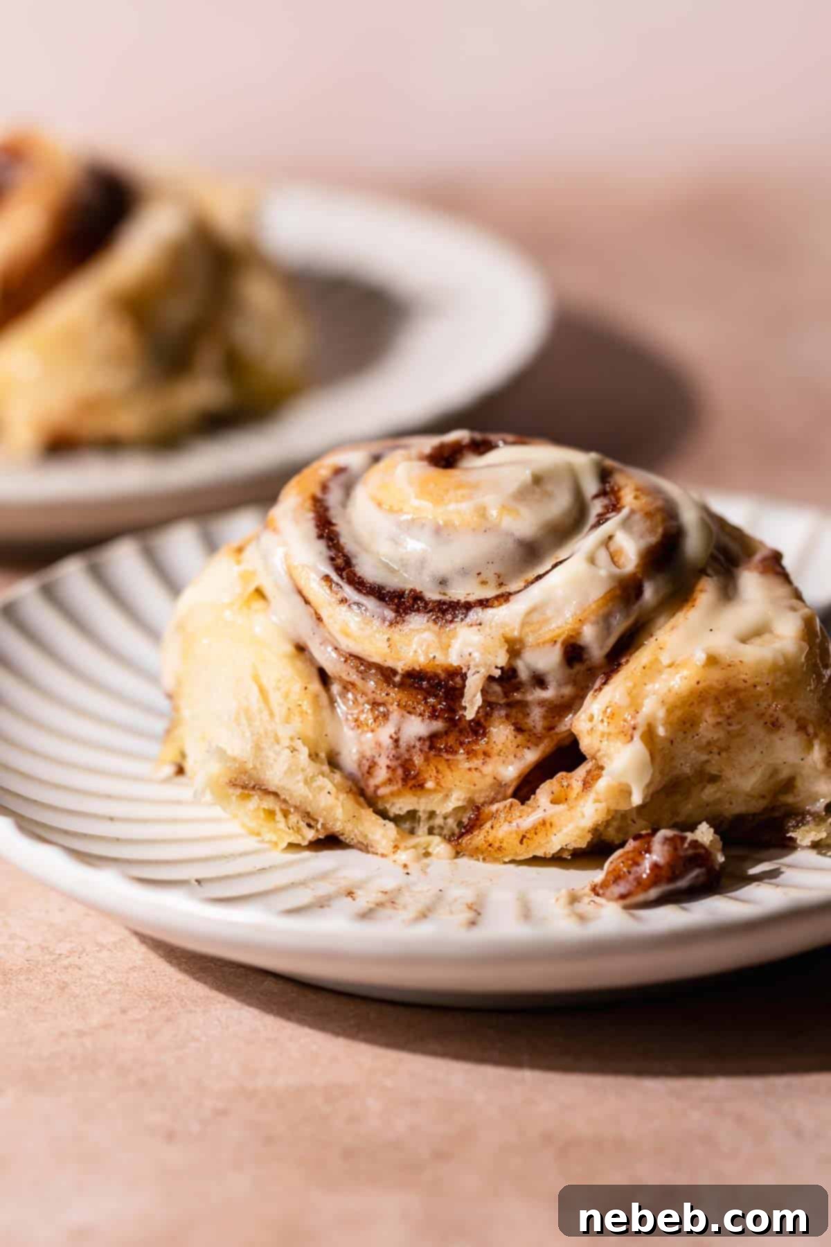 A giant super gooey cinnamon roll on a plate, showcasing its soft, pillowy texture and generous cream cheese frosting.