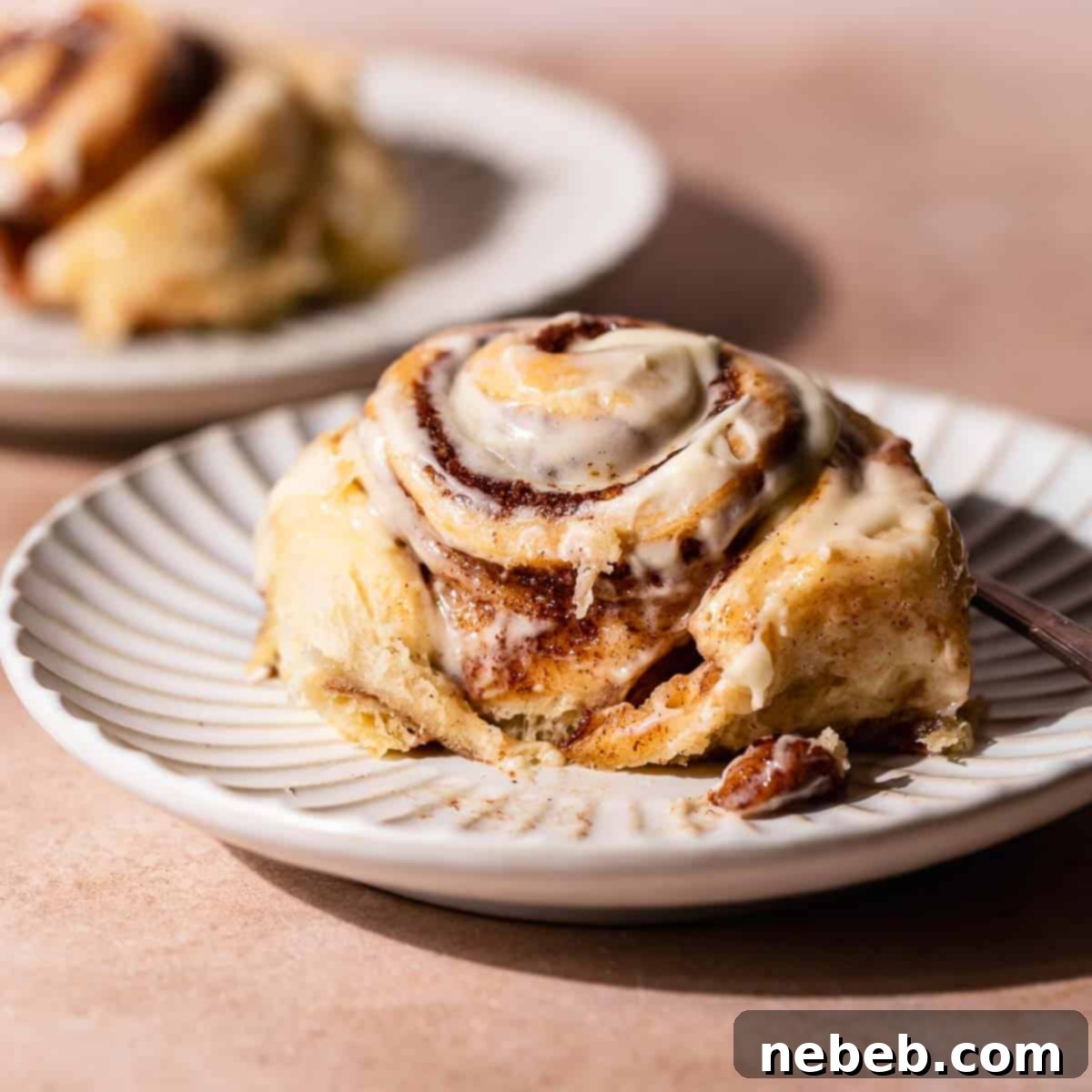 A giant super gooey cinnamon roll on a plate, featuring cream cheese frosting and a soft, pillowy texture.