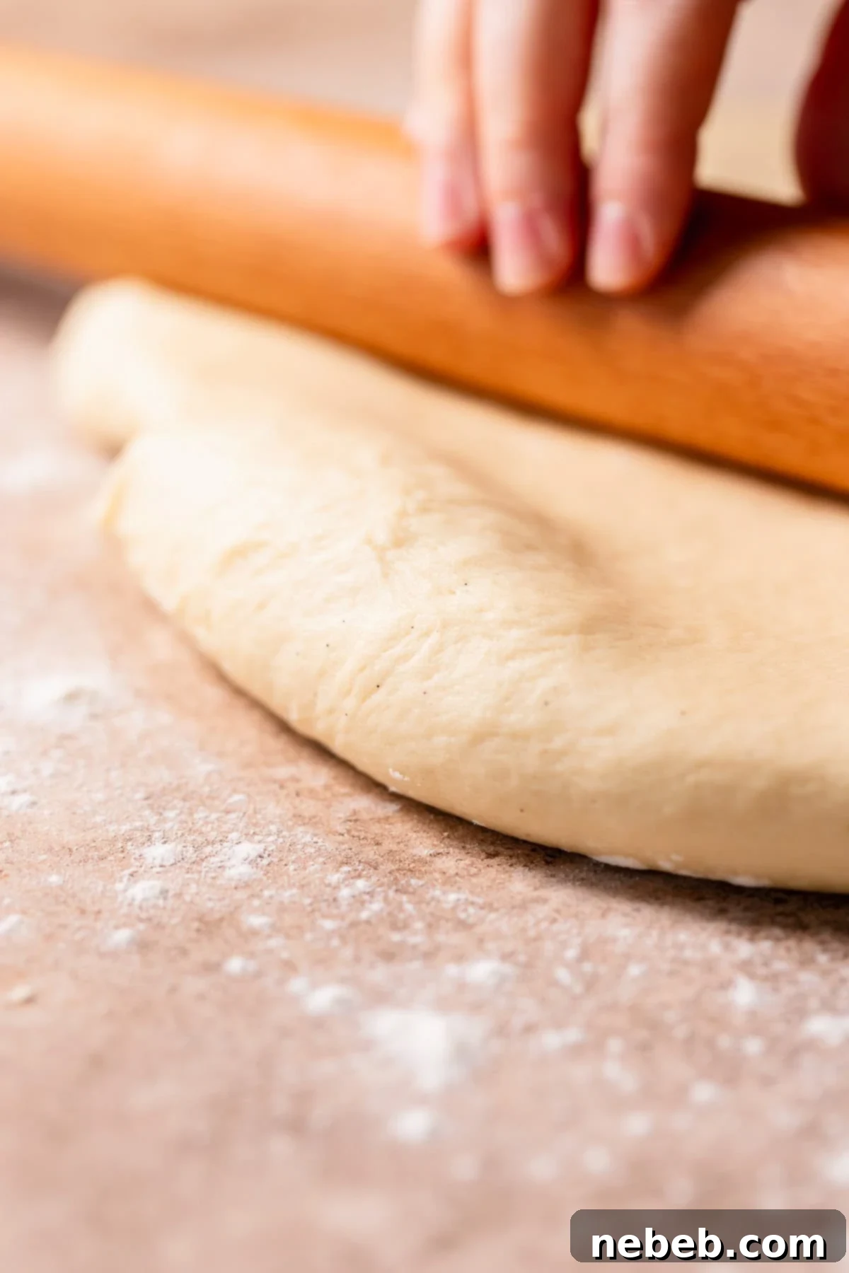 A rolling pin rolling out cinnamon roll dough into a large rectangle.