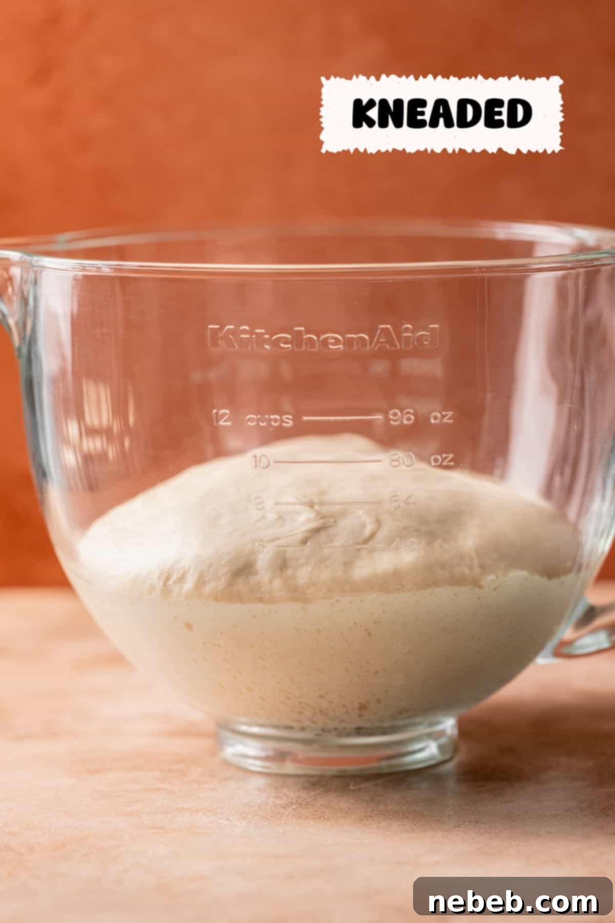 A glass mixing bowl with the perfectly kneaded dough after it has risen, showing significant volume.